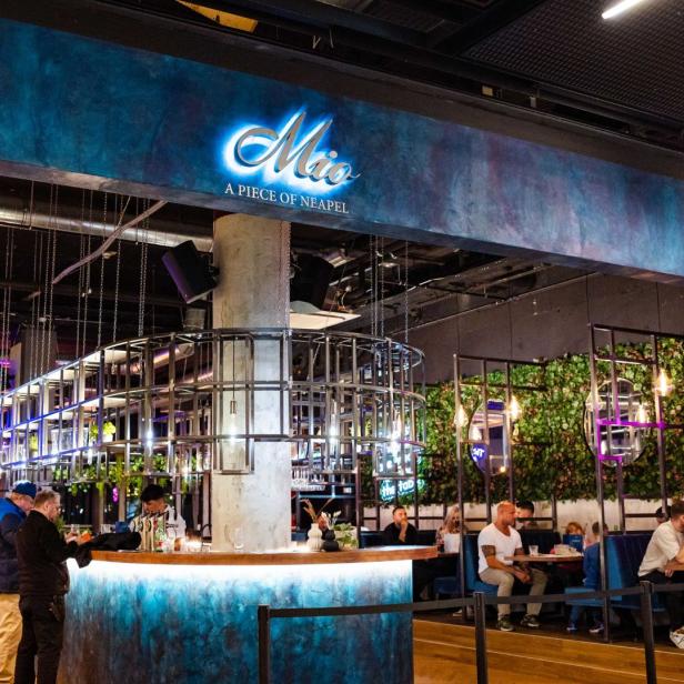 Innenansicht des Restaurants „Mio A Piece of Neapel“ mit Gästen an Tischen und an der Bar.