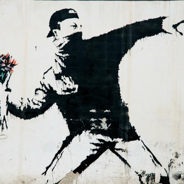 Ein Banksy-Graffiti zeigt eine Person, die statt eines Molotowcocktails einen Blumenstrauß wirft.