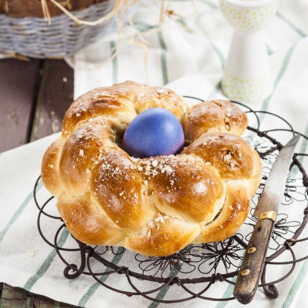 Ein Osterkranz mit einem blauen Ei in der Mitte steht auf einem Tisch.