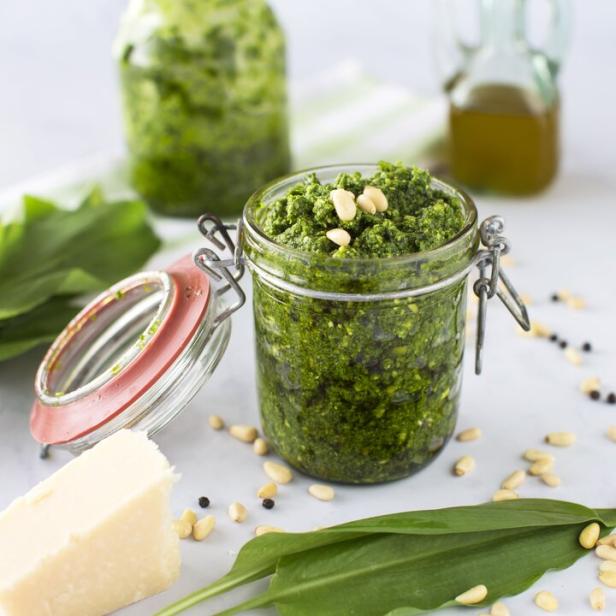 Ein Glas Bärlauchpesto mit Pinienkernen und Parmesan auf einem Tisch.