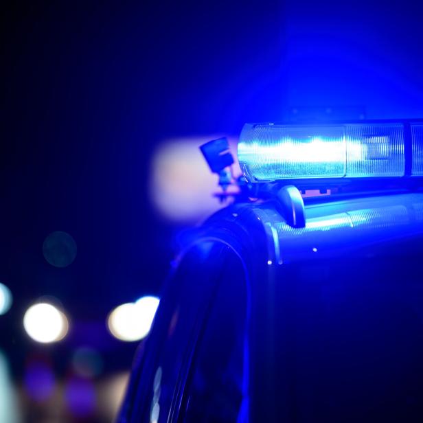Blaulicht leuchtet auf dem Dach eines Einsatzfahrzeugs in der Dunkelheit.