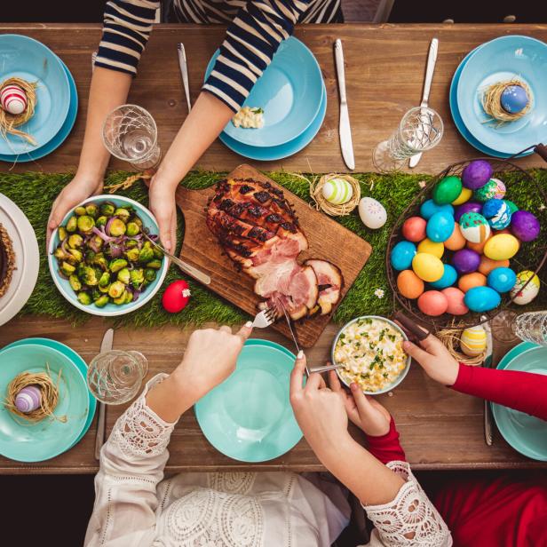 Ein reich gedeckter Ostertisch mit Schinken, Kuchen, Eiern und Beilagen.