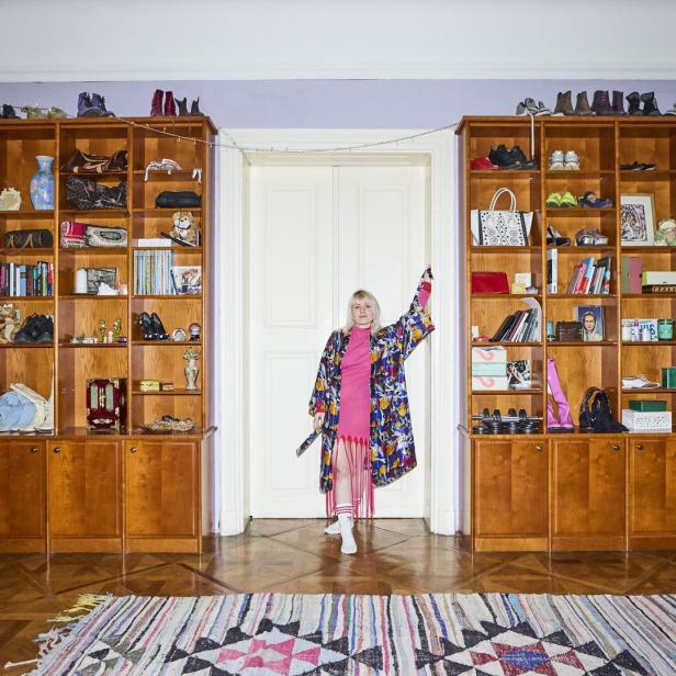 Eine Frau in einem bunten Kimono steht in einem Raum mit vollen Bücherregalen.
