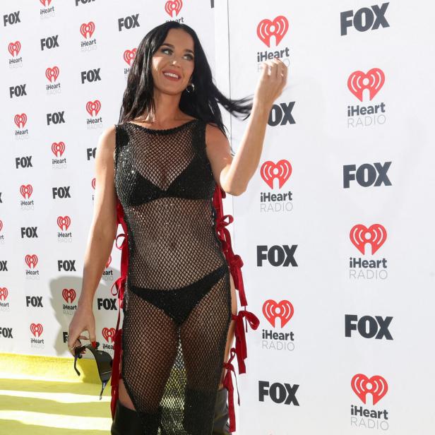 Katy Perry posiert vor einer Wand mit Logos von Fox und iHeart Radio.
