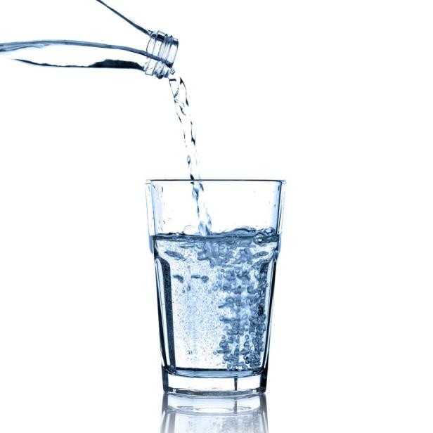 Wasser wird aus einer Flasche in ein Glas gegossen.