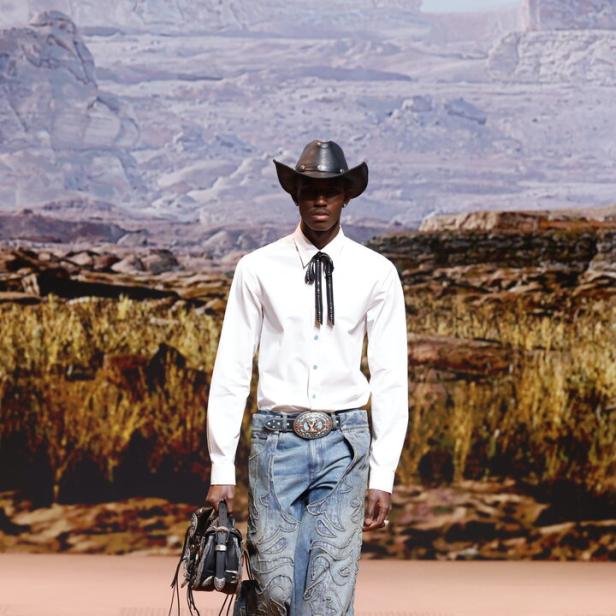 Ein Mann im Western-Look mit Cowboyhut und bestickter Jeans auf einem Laufsteg.