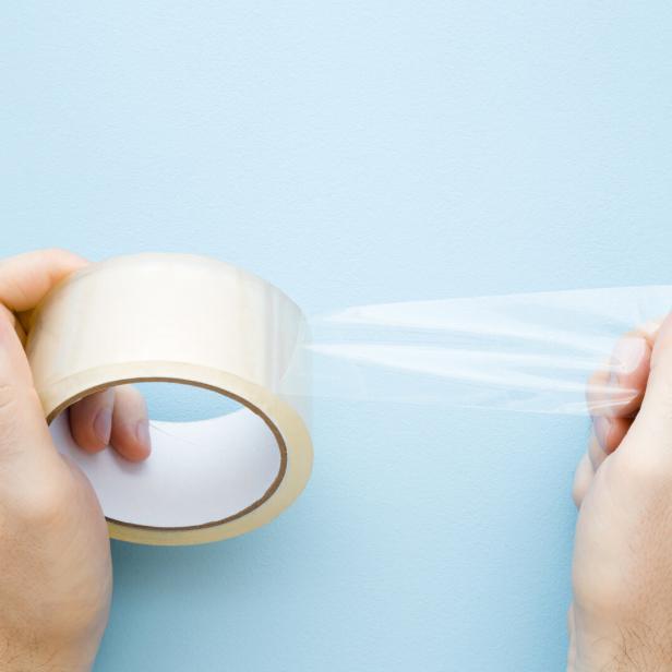 Eine Rolle transparentes Klebeband wird von zwei Händen gehalten.