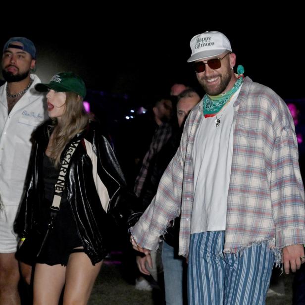 Ein Mann mit „Happy Gilmore“-Kappe und Sonnenbrille hält Händchen mit einer Frau auf einem Festival.