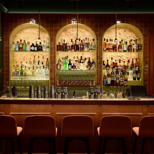 Eine Bar mit einer großen Auswahl an Spirituosen und Barhockern vor dem Tresen.