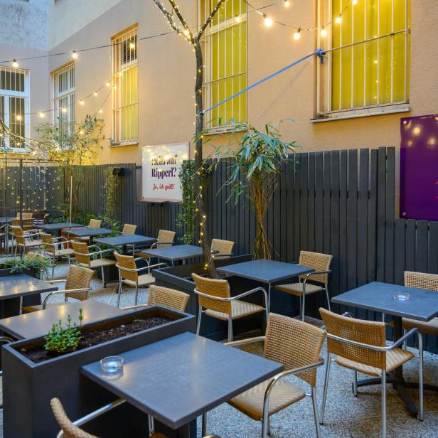 Ein Außenbereich des Restaurants „Jack the Ripperl“ mit Tischen und Stühlen.