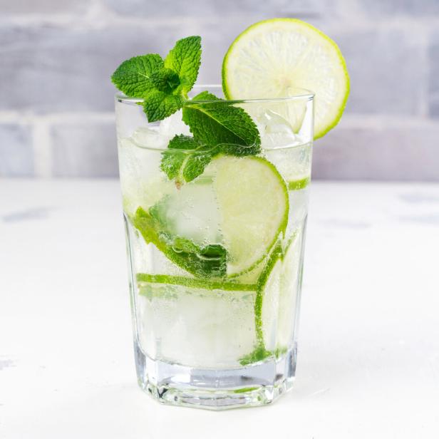 Ein Glas mit einem erfrischenden Getränk, garniert mit Limetten und Minze.