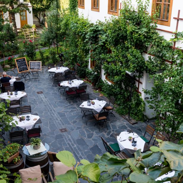 Der Innenhof von Schreiners Gastwirtschaft mit Tischen und üppigem Grün.