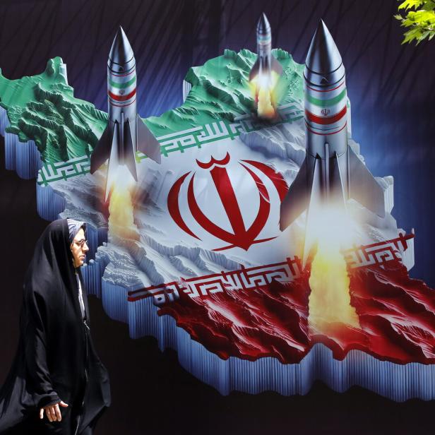 Eine Frau in Teheran geht an einem Wandbild vorbei