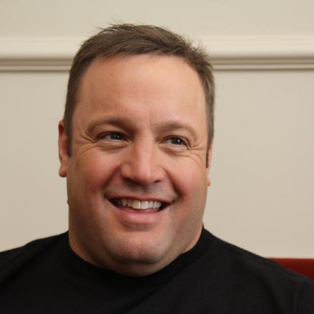 Ein lächelnder Kevin James vor einer hellen Wand.