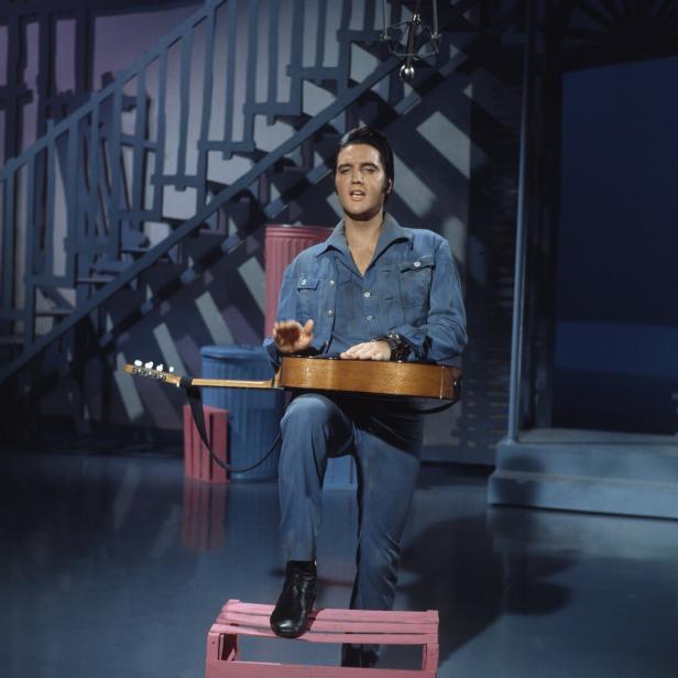 Elvis Presley spielt ein Instrument, während er auf einer kleinen Kiste steht.