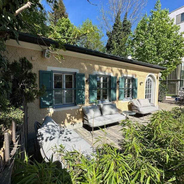 Ein gelbes Gebäude mit grünen Fensterläden und einer Terrasse mit Gartenmöbeln.