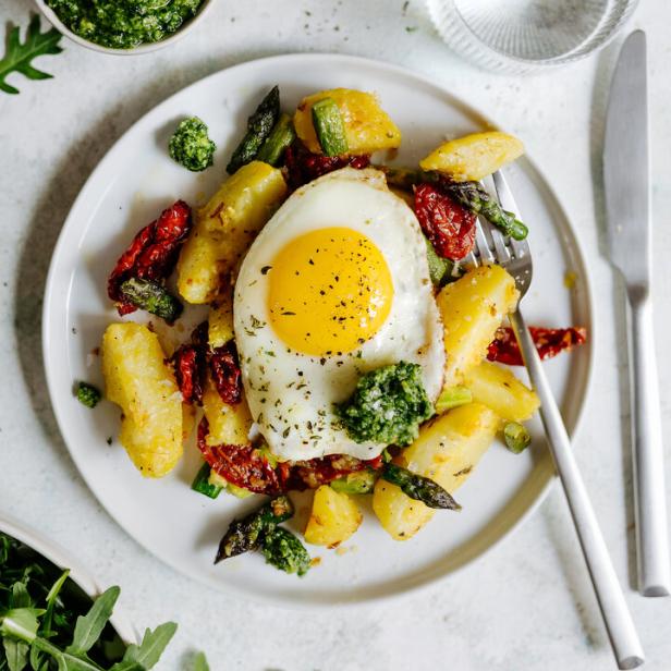 Ein Teller mit Bratkartoffeln, Spargel, getrockneten Tomaten, Pesto und einem Spiegelei.