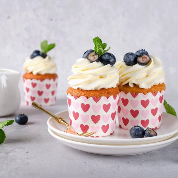 Cupcakes mit Frischkäse-Topping und Blaubeeren auf einem Teller.