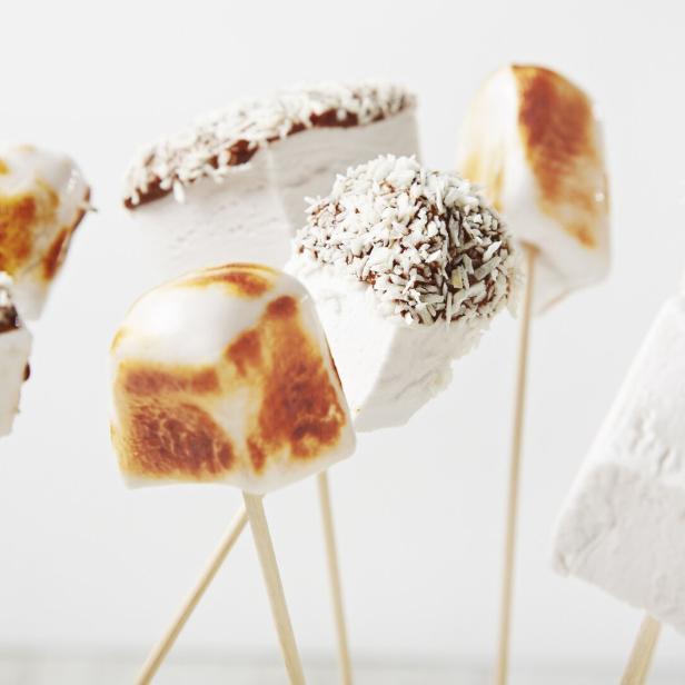 Marshmallows mit Schokolade und Kokosraspeln auf Spießen.