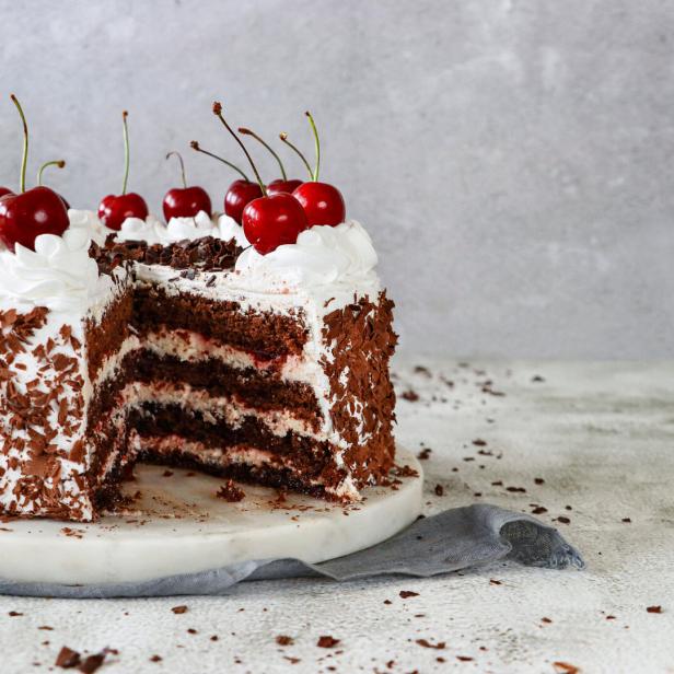 Angeschnittene Torte mit Schlagobers und Kirschen.