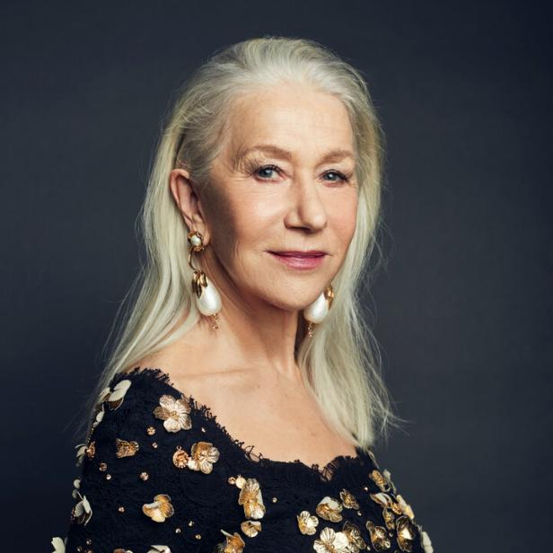Helen Mirren trägt ein schwarzes Kleid mit goldenen Blumen und auffällige Ohrringe.