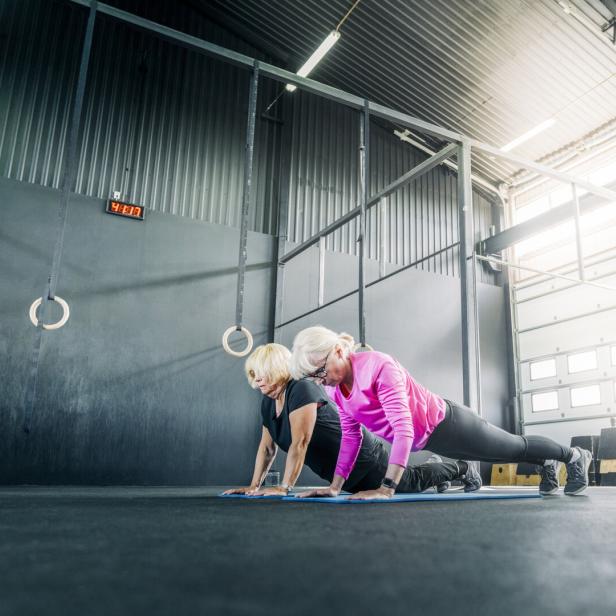 Zwei ältere Frauen machen Liegestütze in einem Fitnessstudio.