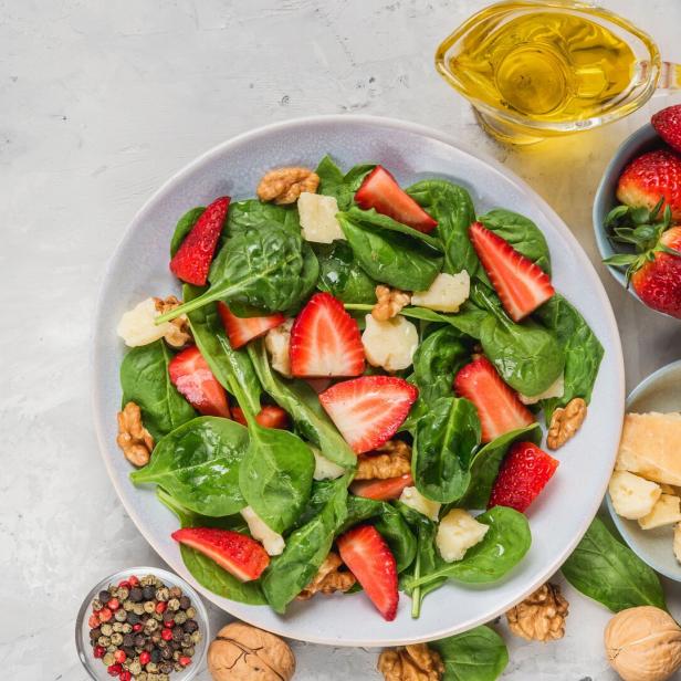 Ein Teller mit Salat aus Spinat, Erdbeeren, Walnüssen und Käsewürfeln.
