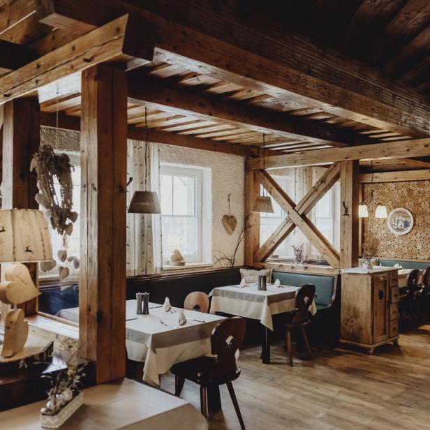 Innenansicht des Restaurants Puchegger Wirt mit Holzbalken und gedeckten Tischen.