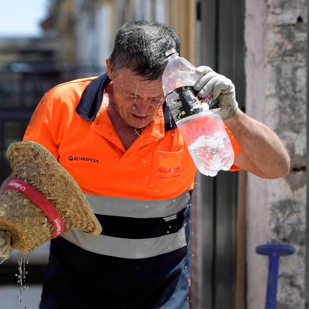 Ein Bauarbeiter schüttet sich Wasser über den Kopf, um sich bei Hitze abzukühlen.