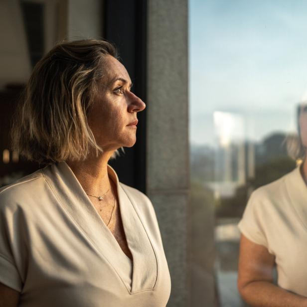 Eine Frau mittleren Alters blickt aus dem Fenster.