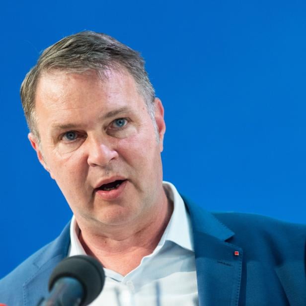 Andreas Babler gestikuliert vor einem blauen Hintergrund.