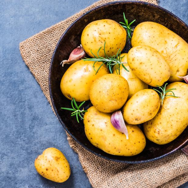 Gelbe Kartoffeln mit Knoblauch und Rosmarin in einer Bratpfanne.