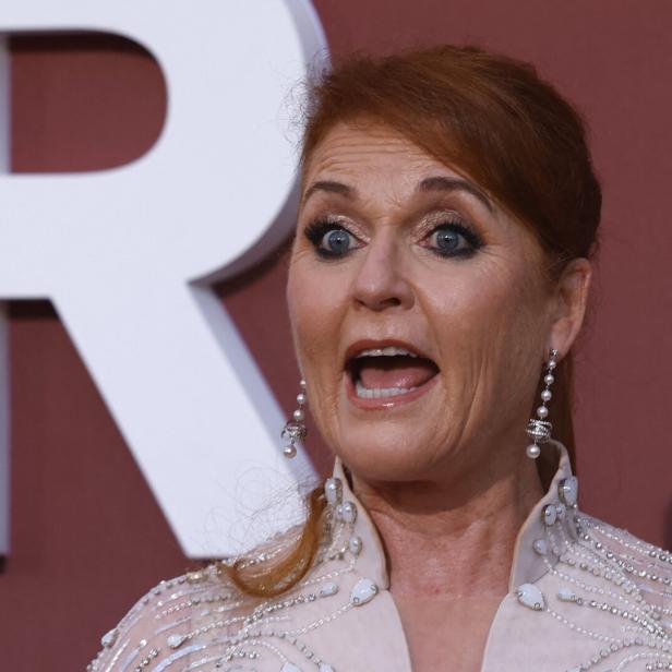 Sarah Ferguson mit offenem Mund vor einem roten Hintergrund.