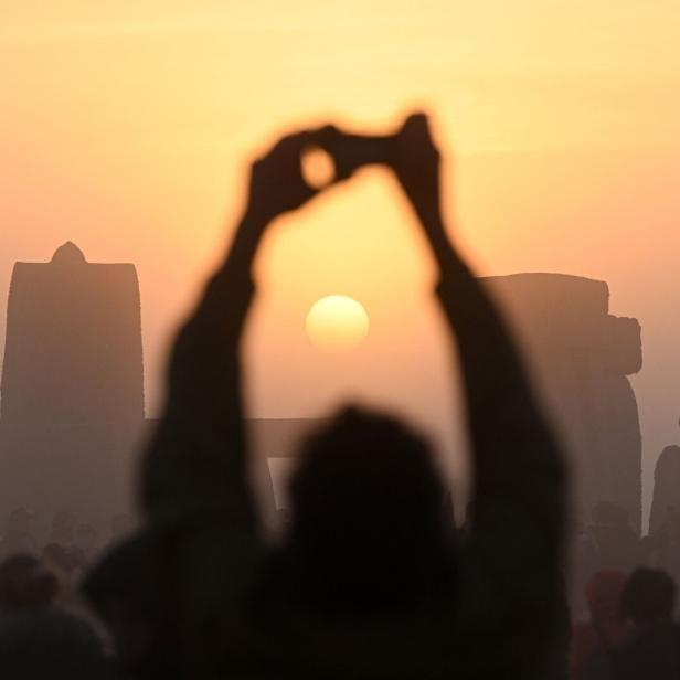 Menschen beobachten den Sonnenaufgang in Stonehenge und machen Fotos.