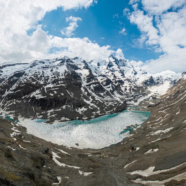 Der Großglockner Gletscher und ein teilweise gefrorener See in einer Berglandschaft.
