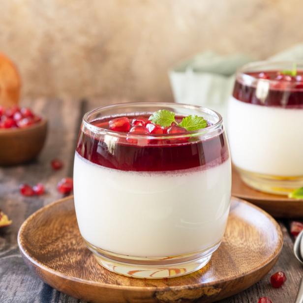 Zwei Gläser Puddingeis mit Granatapfel und Minze garniert.