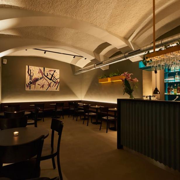 Innenansicht der Olinda Bar mit Tischen, Bar und Kunst an der Wand.