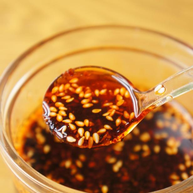 Scharfes Chiliöl aus China in einem Glas mit einem Löffel.