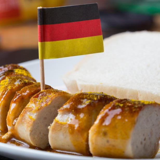 Auf einer Currywurst steckt eine Papierflagge mit den deutschen Farben Schwarz, Rot, Gold.