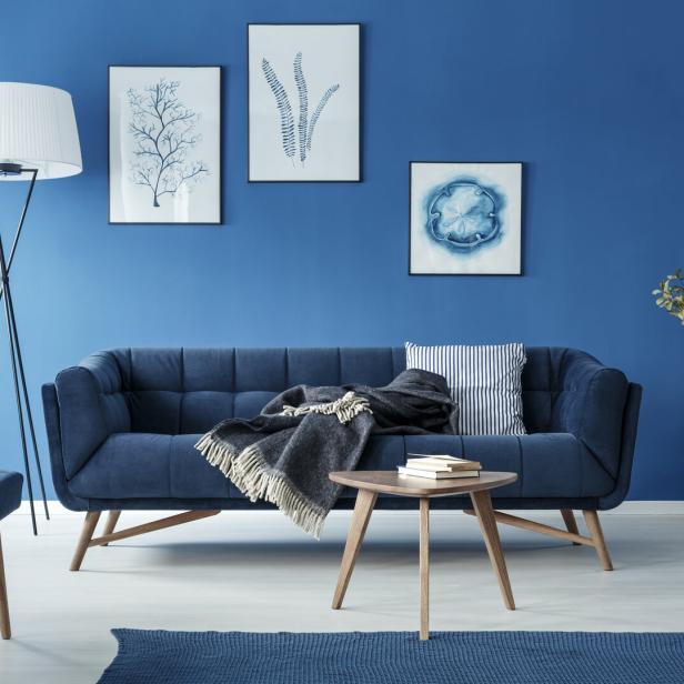 Ein blaues Wohnzimmer mit Sofa, Lampe und Dekorationen.