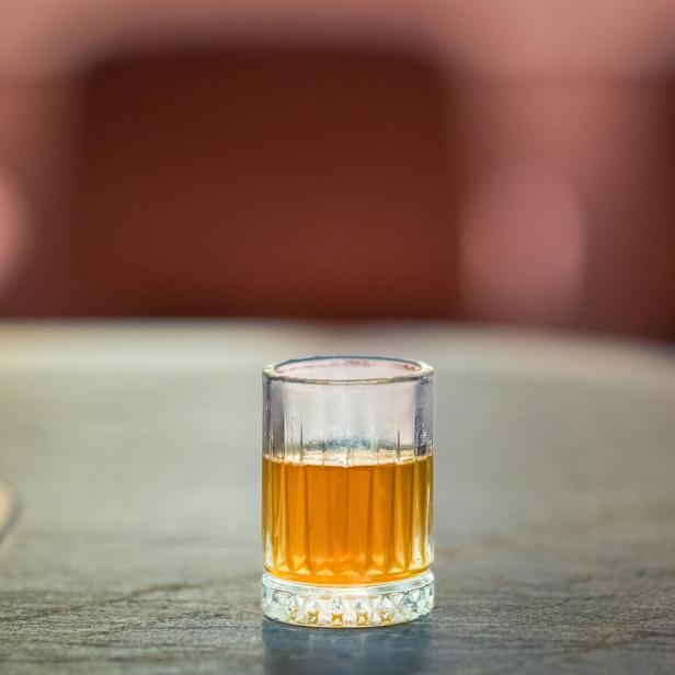 Ein Glas „Rum-Shot Butter Madre“ steht auf einem Tisch.
