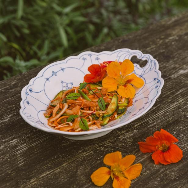 Salat mit essbaren Blüten auf einem Teller.