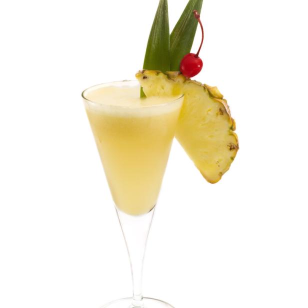 Ein Ananas-Cocktail in einem Glas, garniert mit einer Ananasscheibe und einer Kirsche.