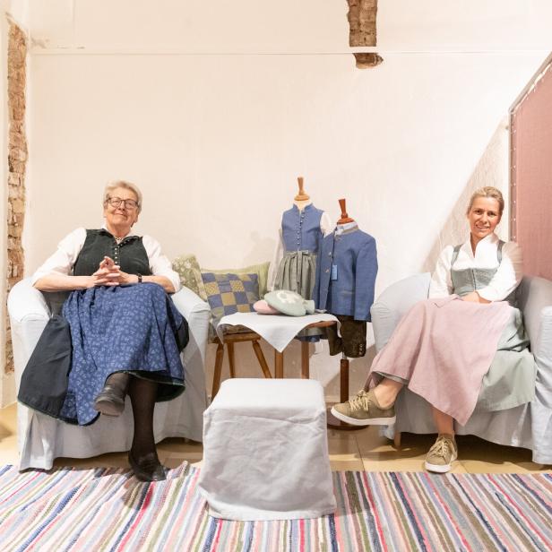 Zwei Frauen sitzen in Tracht in einem Geschäft.