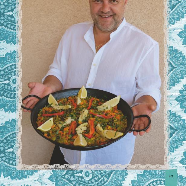 Ein Mann präsentiert eine Gemüse-Paella.