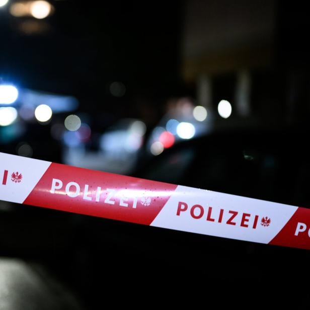 Absperrband mit der Aufschrift „Polizei“ vor unscharf beleuchteter Straße in der Nacht.