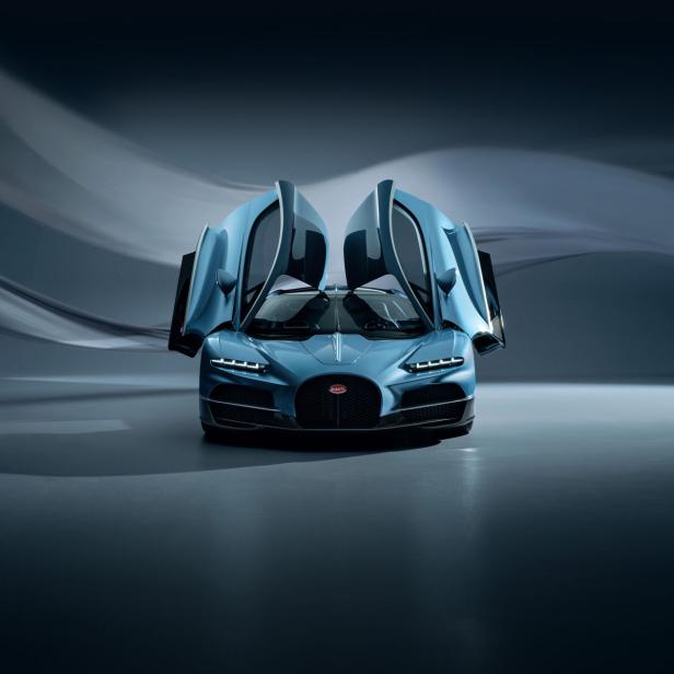 Ein blauer Bugatti mit geöffneten Flügeltüren steht in einem Studio.