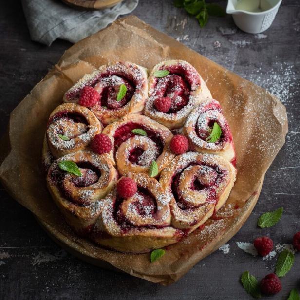 Ein Kranz aus Himbeer-Schnecken mit Puderzucker und Minze verziert.