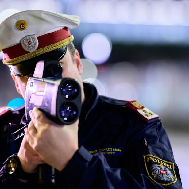 Ein Polizist in Uniform mit Mütze bedient ein Radargerät zur Geschwindigkeitsmessung.