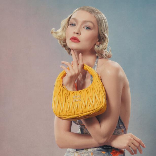 Gigi Hadid posiert mit einer gelben Miu Miu Handtasche.